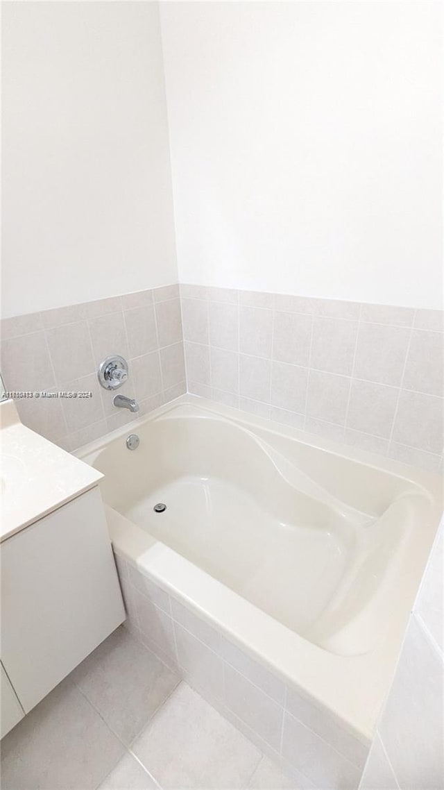 bathroom featuring tile patterned flooring, vanity, and tiled bath