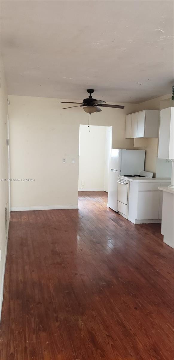 unfurnished living room with ceiling fan and dark wood-type flooring