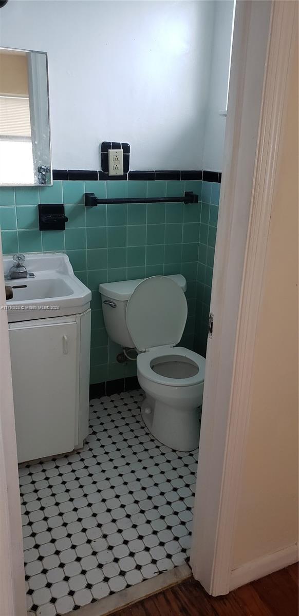 bathroom featuring vanity, toilet, and tile walls