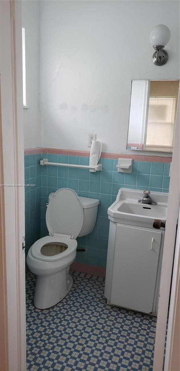 bathroom featuring vanity, tile walls, and toilet