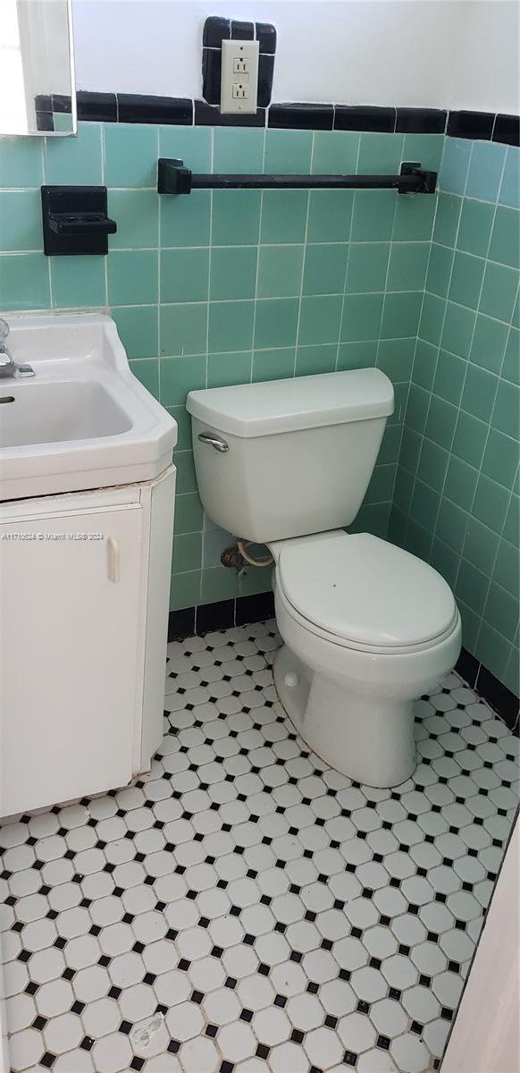 bathroom featuring vanity, toilet, and tile walls