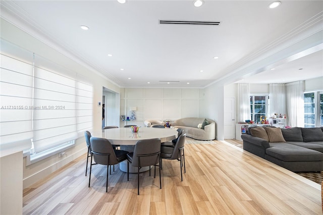 dining space with light hardwood / wood-style floors and ornamental molding