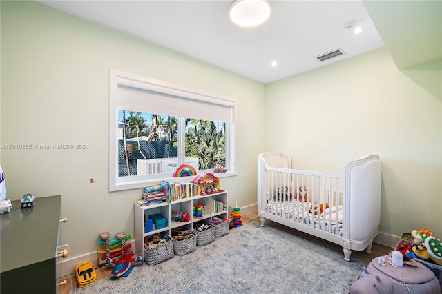 bedroom featuring a nursery area and hardwood / wood-style flooring