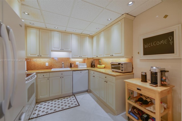 kitchen featuring light tile patterned flooring, a toaster, white appliances, a sink, and light countertops