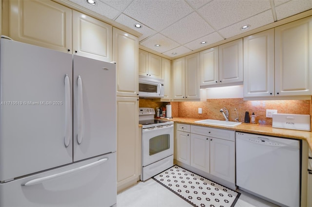 kitchen featuring white appliances, decorative backsplash, light countertops, a sink, and recessed lighting