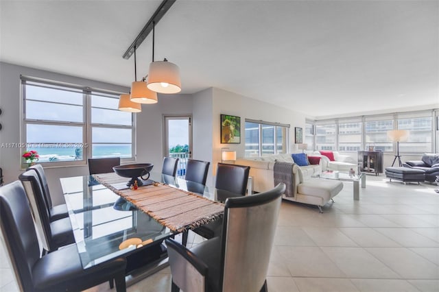 dining space with a water view and light tile patterned floors