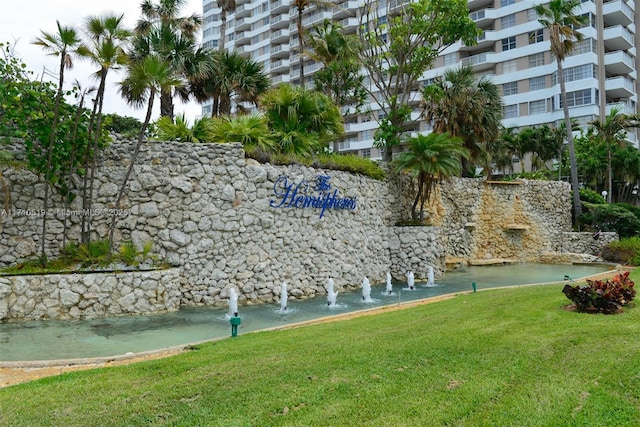 community sign with a water view and a yard