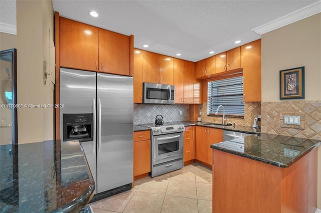 kitchen with sink, dark stone countertops, ornamental molding, light tile patterned floors, and stainless steel appliances