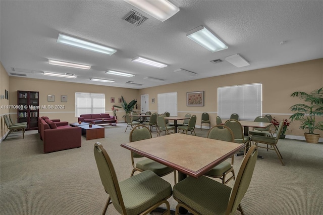 dining room with a textured ceiling and light colored carpet