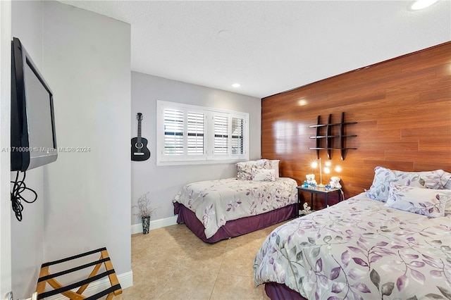 bedroom featuring wood walls, light tile patterned floors, and a textured ceiling