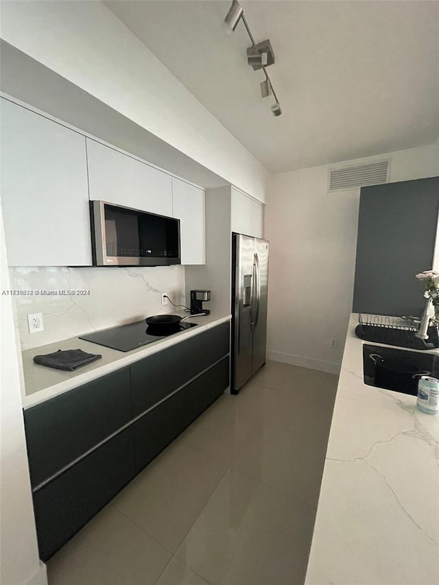 kitchen featuring appliances with stainless steel finishes, track lighting, sink, light tile patterned floors, and white cabinets