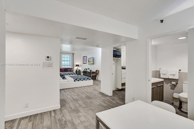 bedroom featuring connected bathroom and light hardwood / wood-style flooring