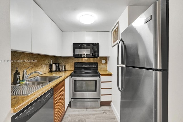 kitchen with sink, backsplash, appliances with stainless steel finishes, white cabinets, and light wood-type flooring