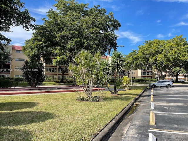 view of property's community featuring uncovered parking and a yard