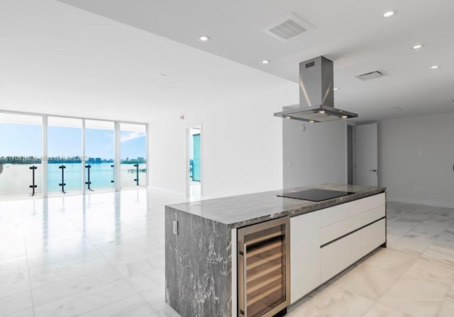 kitchen featuring white cabinets, a water view, black electric cooktop, island range hood, and beverage cooler