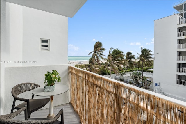 balcony featuring a water view and a beach view