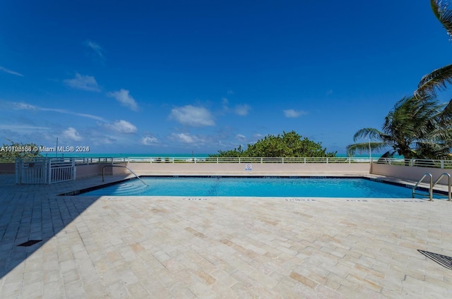 view of pool with a patio area and a water view