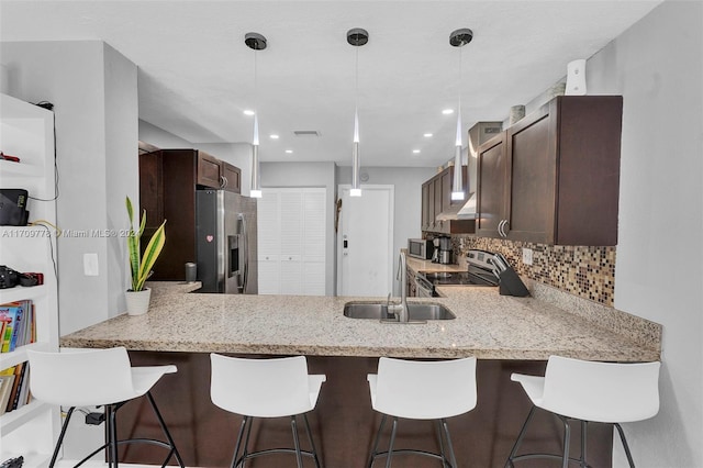 kitchen featuring pendant lighting, sink, tasteful backsplash, kitchen peninsula, and stainless steel appliances