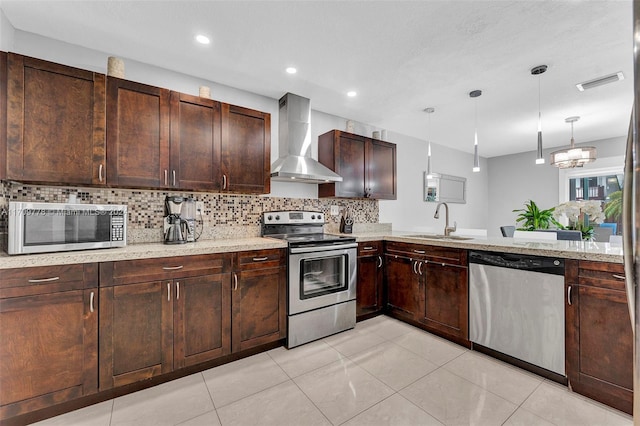 kitchen featuring sink, hanging light fixtures, wall chimney exhaust hood, a notable chandelier, and stainless steel appliances