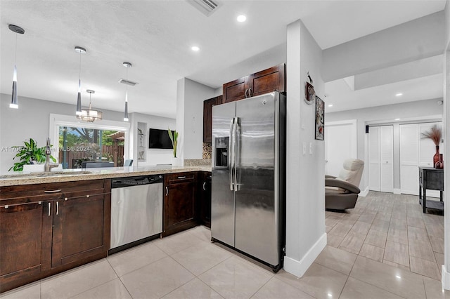 kitchen featuring light stone counters, stainless steel appliances, hanging light fixtures, and an inviting chandelier