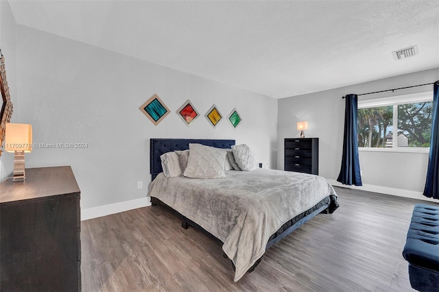 bedroom with wood-type flooring and a textured ceiling