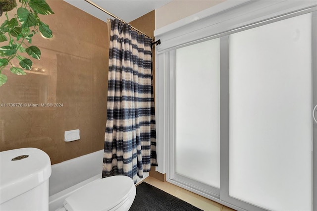 bathroom with shower / bath combination with curtain, toilet, and a wealth of natural light