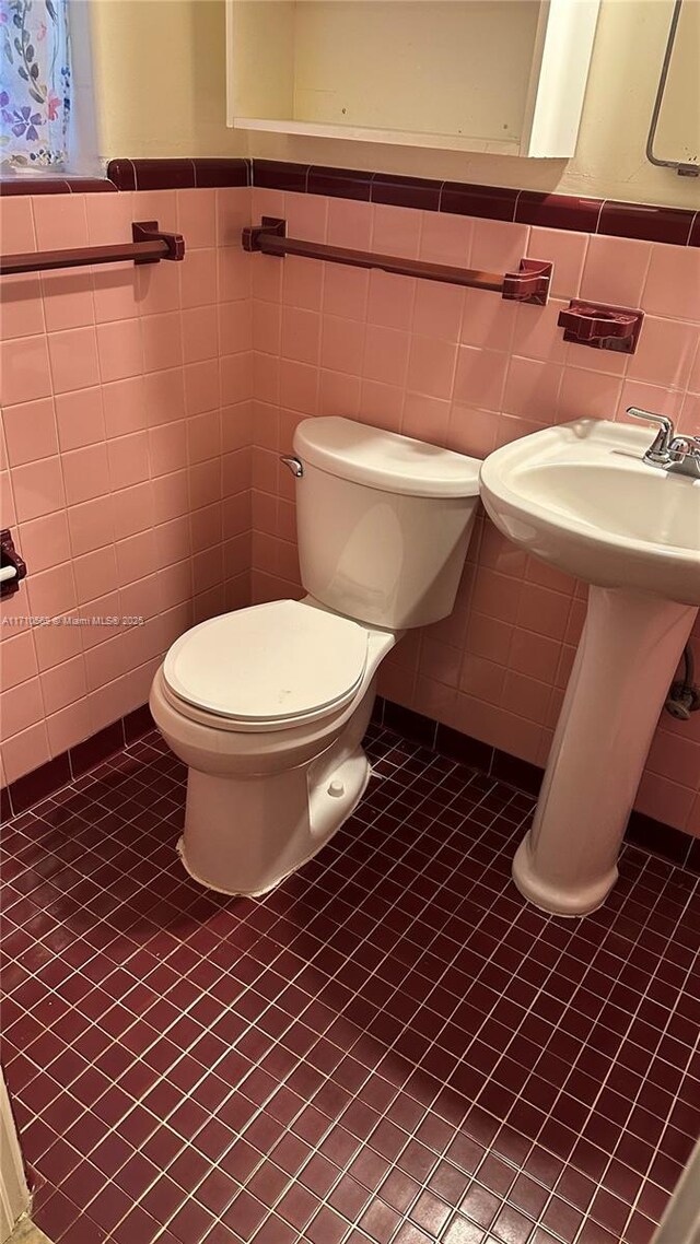 bathroom with tile patterned flooring, tile walls, and toilet