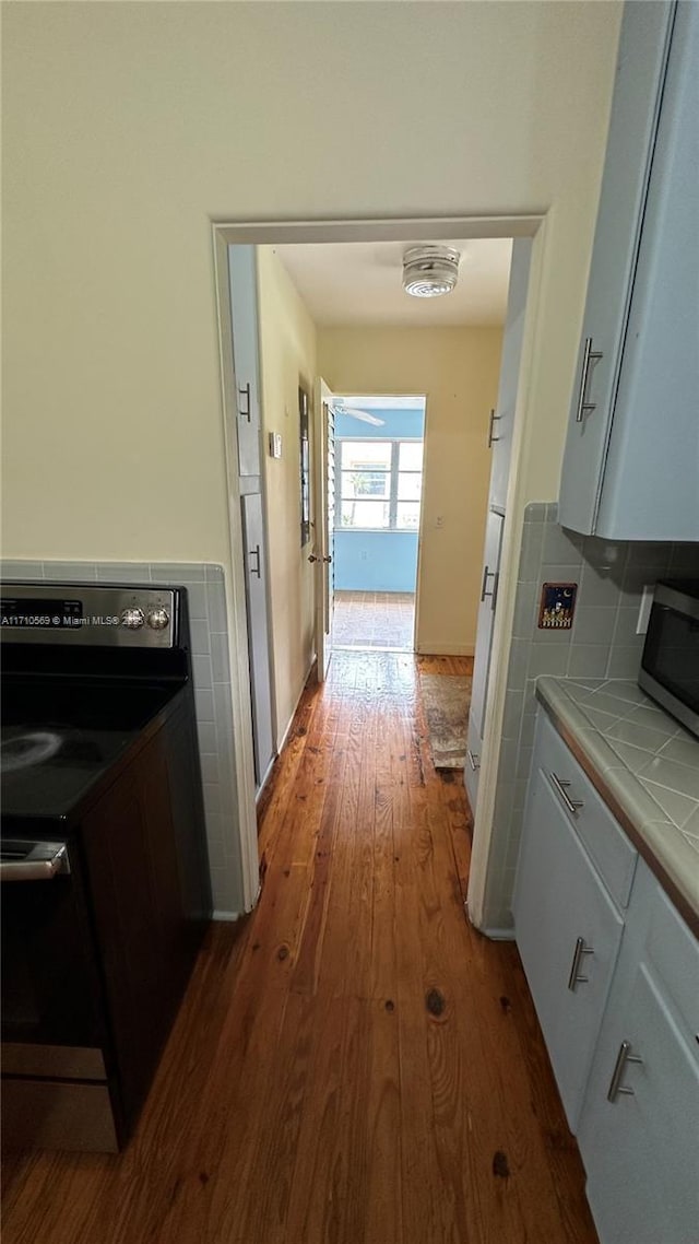 corridor featuring hardwood / wood-style floors and tile walls