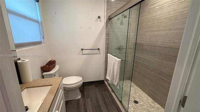 bathroom with vanity, hardwood / wood-style flooring, a shower with shower door, and toilet