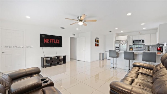 living room featuring light tile patterned floors, ceiling fan, and sink