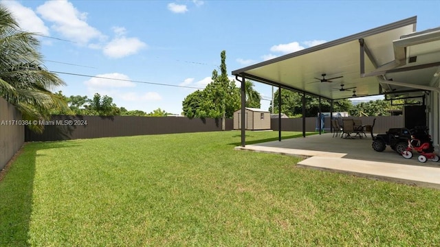 view of yard featuring a storage unit, ceiling fan, and a patio