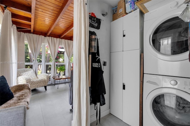 clothes washing area featuring cabinets, wood ceiling, and stacked washer and clothes dryer