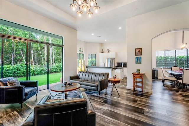 living room featuring dark wood-style floors, recessed lighting, a high ceiling, and an inviting chandelier