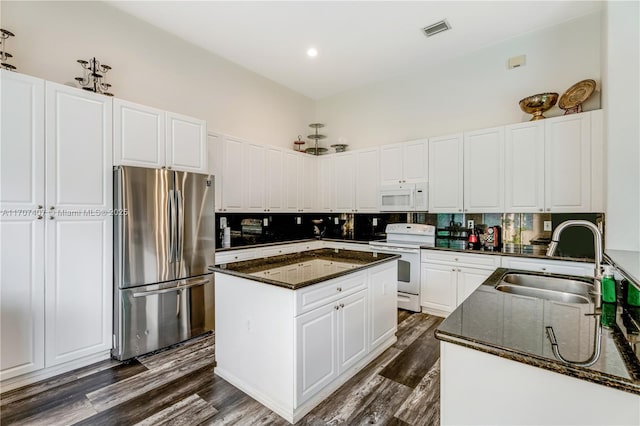 kitchen with a center island, visible vents, backsplash, a sink, and white appliances