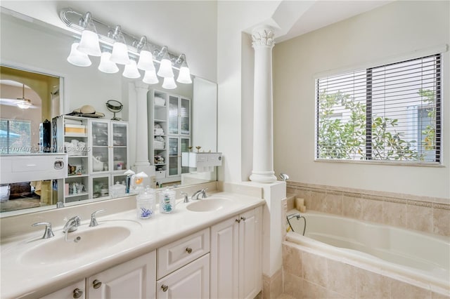 bathroom with double vanity, a garden tub, decorative columns, and a sink