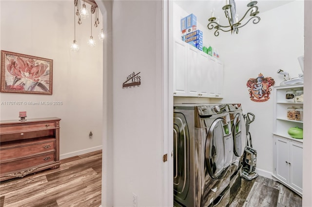 washroom featuring cabinet space, baseboards, wood finished floors, separate washer and dryer, and a notable chandelier