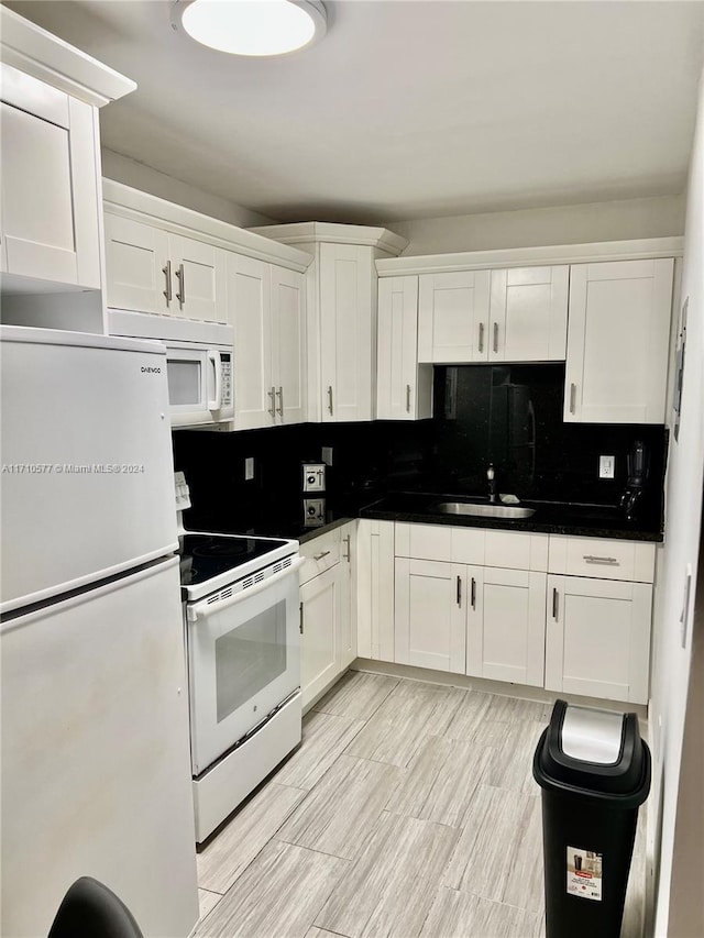 kitchen with white appliances, sink, decorative backsplash, light wood-type flooring, and white cabinetry