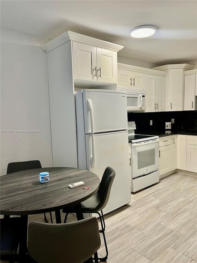 kitchen featuring white cabinets, decorative backsplash, and white appliances