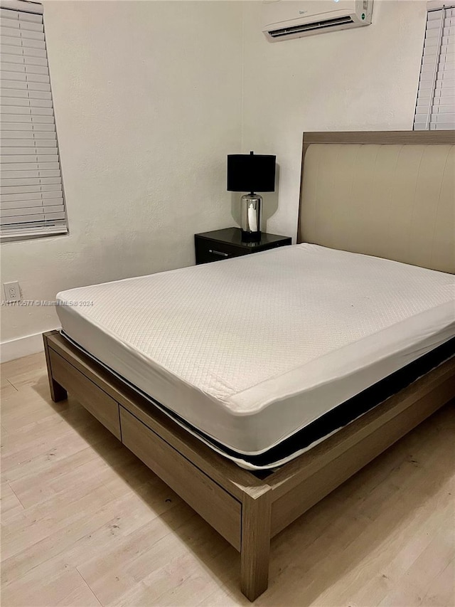 bedroom featuring a wall unit AC and light hardwood / wood-style floors