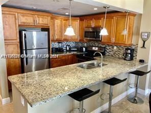 kitchen with kitchen peninsula, appliances with stainless steel finishes, pendant lighting, and a breakfast bar area