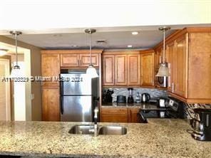 3725 S Ocean Dr Unit 1605, Hollywood, FL 33019 - kitchen featuring freestanding refrigerator, stove, brown cabinetry, a peninsula, and pendant lighting
