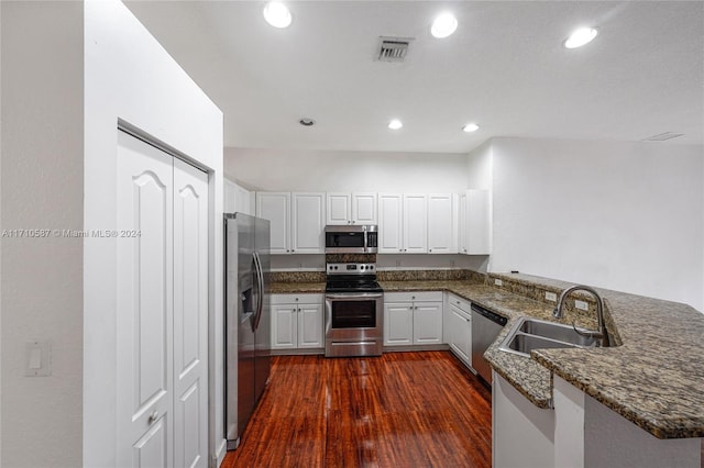 kitchen with kitchen peninsula, white cabinetry, dark wood-type flooring, and stainless steel appliances