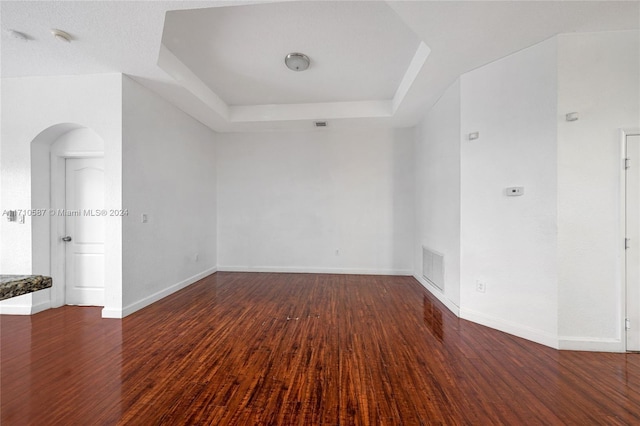 empty room featuring dark hardwood / wood-style flooring and a tray ceiling