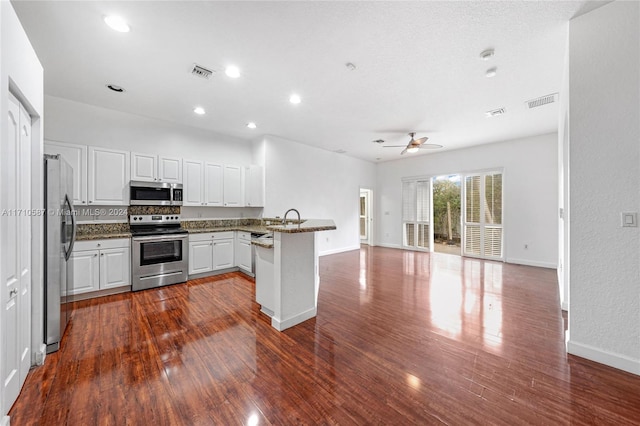 kitchen featuring kitchen peninsula, dark hardwood / wood-style flooring, stainless steel appliances, and white cabinetry