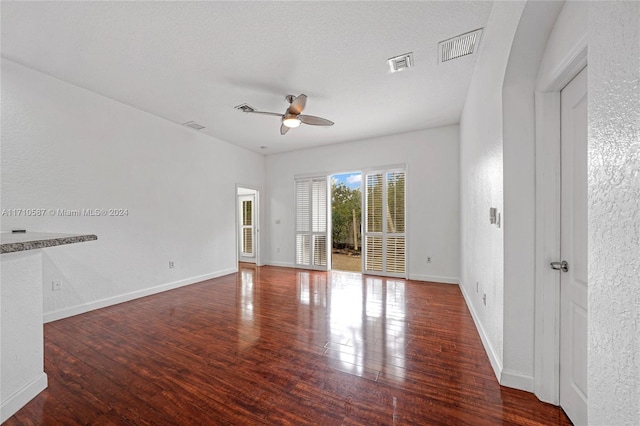 empty room with ceiling fan, dark hardwood / wood-style flooring, and a textured ceiling