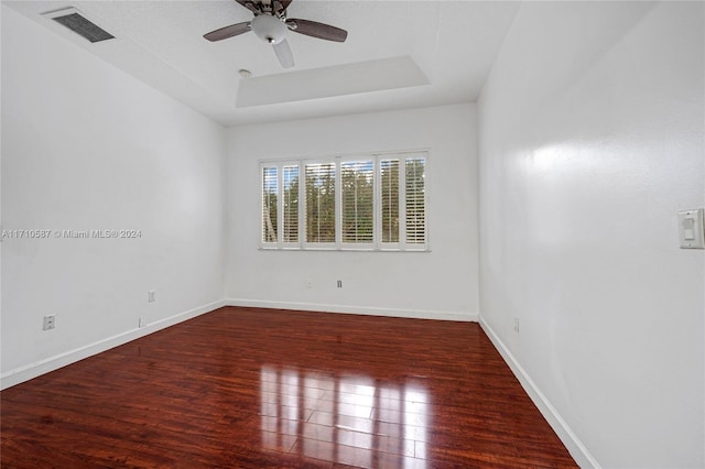 empty room featuring hardwood / wood-style floors, ceiling fan, and a raised ceiling