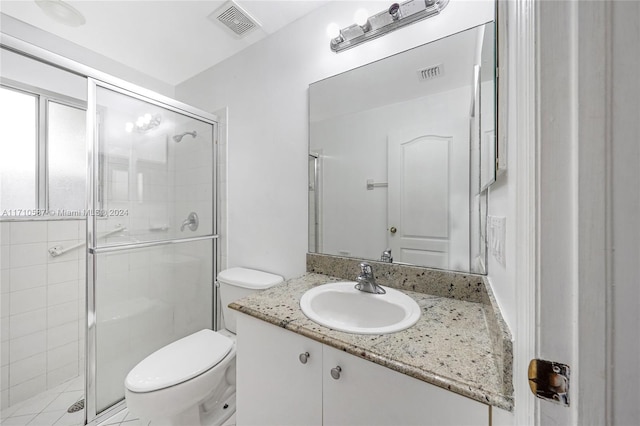 bathroom featuring vanity, a shower with shower door, and toilet