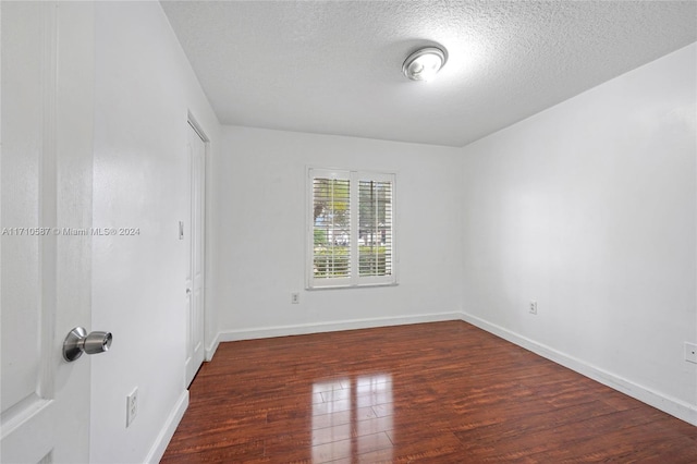 empty room with a textured ceiling and dark wood-type flooring