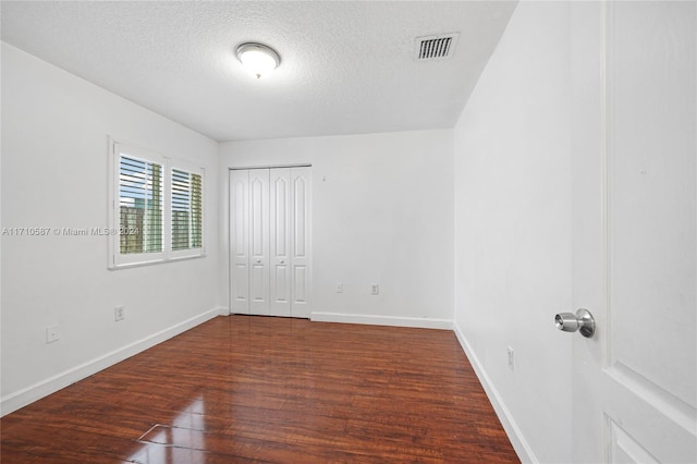 empty room featuring a textured ceiling and dark hardwood / wood-style flooring