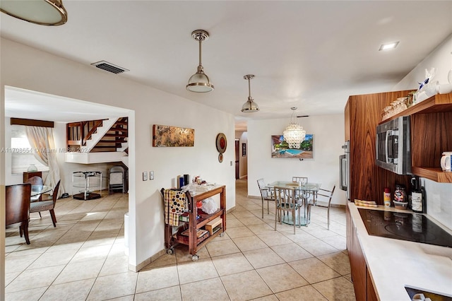 kitchen with black electric stovetop, light tile patterned flooring, and decorative light fixtures